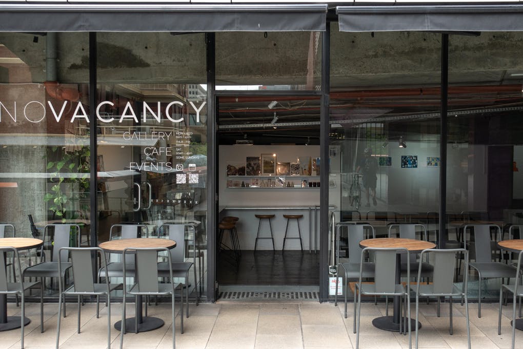 The exterior of a cafe with chairs out front.